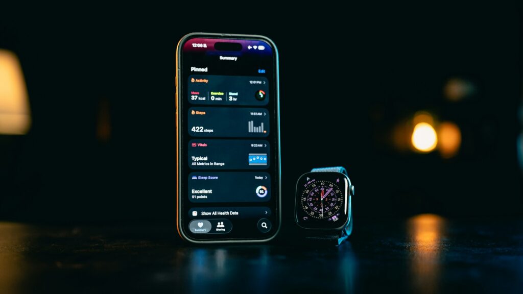 An iPhone displaying health data next to an Apple Watch, showcasing fitness metrics like steps and activity levels in a dark setting.