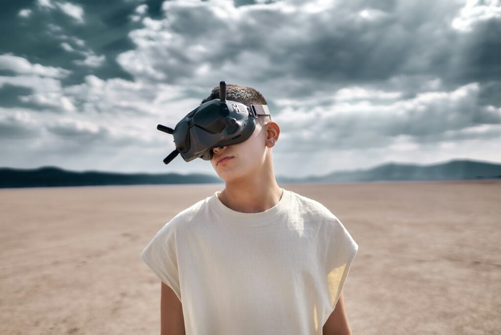 A person standing on a vast barren landscape, wearing a virtual reality headset, under a cloudy sky.