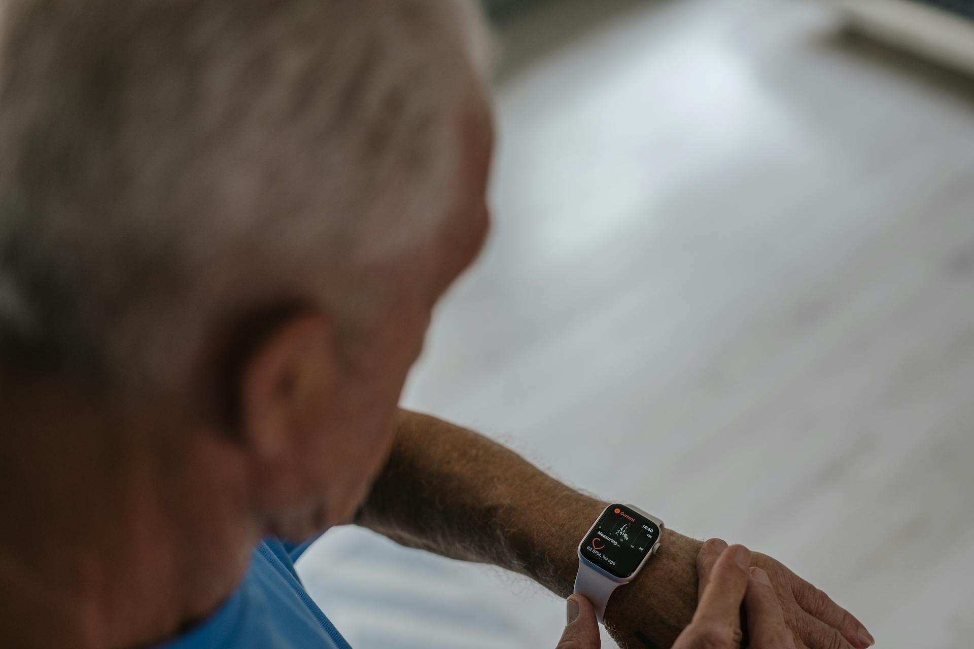 An older man checks his smartwatch displaying health data on his wrist, highlighting active monitoring and fitness tracking.