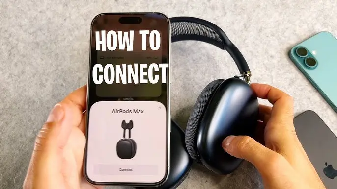 A person holds an iPhone displaying a "HOW TO CONNECT" tutorial screen for AirPods Max, while their other hand holds the black over-ear headphones. In the background, a light blue iPhone and another device are visible on a gray surface.