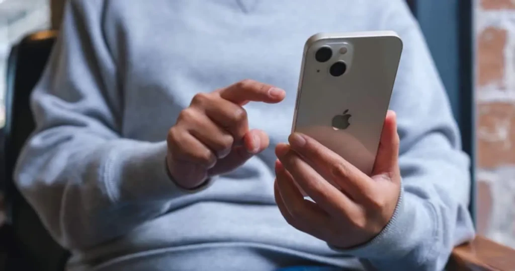 Person using an iPhone holding the device with one hand and tapping the screen during a phone call