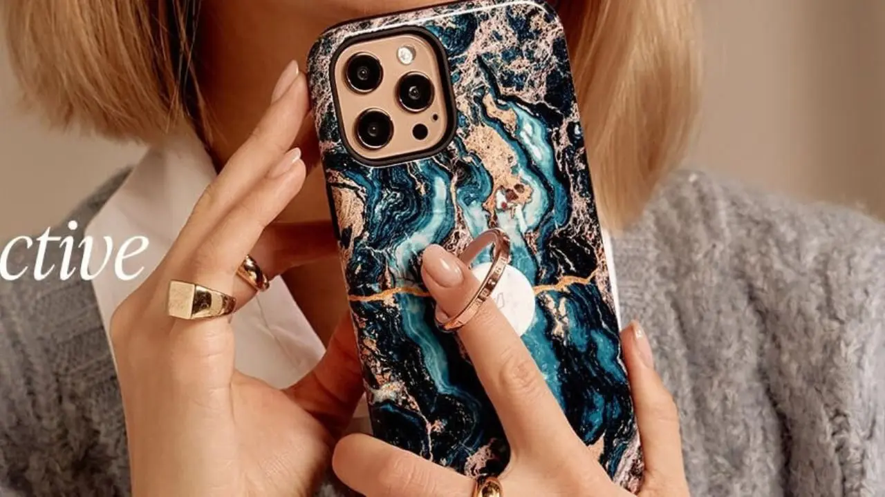 Person holding a smartphone with a blue and gold marble-patterned case featuring a circular ring grip on the back