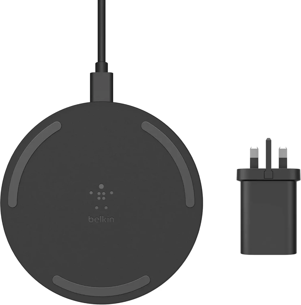 A black Belkin wireless charging pad displayed alongside its matching wall adapter, featuring the Belkin logo and subtle grip pads around the charging surface, illustrating its complete setup for reliable, cable-free power delivery for smartphones and accessories.