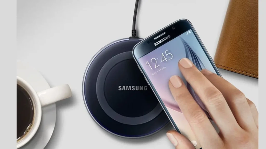 A hand placing a Samsung smartphone onto a dark circular wireless charger next to a cup of coffee and a leather wallet, showcasing real-world convenience and integration into everyday routines with effortless, cable-free charging.