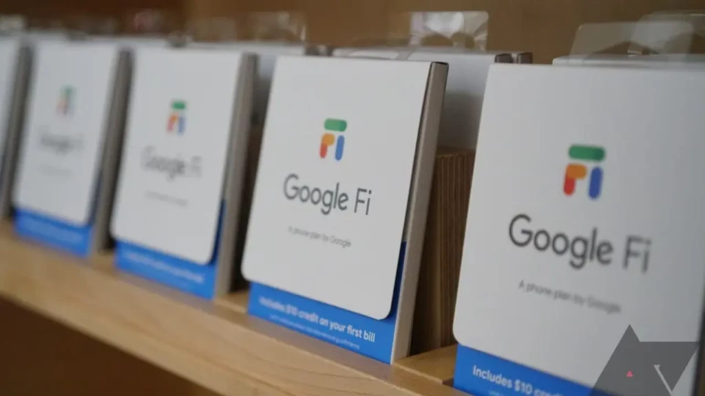 A row of Google Fi promotional cards displayed on a wooden shelf, each labeled “Google Fi, A phone plan by Google” with a blue banner noting “Includes $10 credit on your first bill,” showcasing its retail presence and introductory offer for new subscribers.