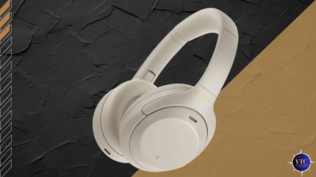 A cream-colored Sony WH-1000XM4 headset displayed at an angle on a textured black-and-gold background, emphasizing its sleek build, gold-accented branding, and minimalist aesthetic for lifestyle and product showcase purposes.