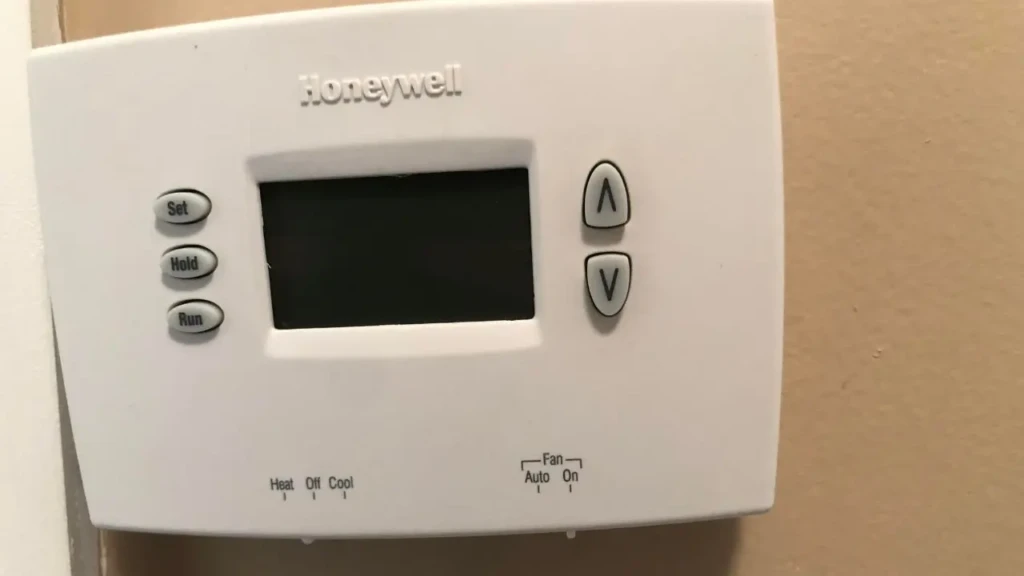 A classic Honeywell non-programmable thermostat with a blank LCD screen, three labeled buttons (Set, Hold, Run) on the left, up/down arrow buttons on the right, and mode switches for Heat/Off/Cool and Fan Auto/On, highlighting its simple, analog-style interface for basic HVAC control.