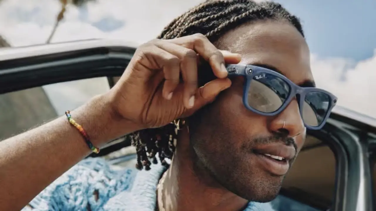 A person with braided hair and a colorful bracelet poses beside a car, against a backdrop of blue skies and palm trees.