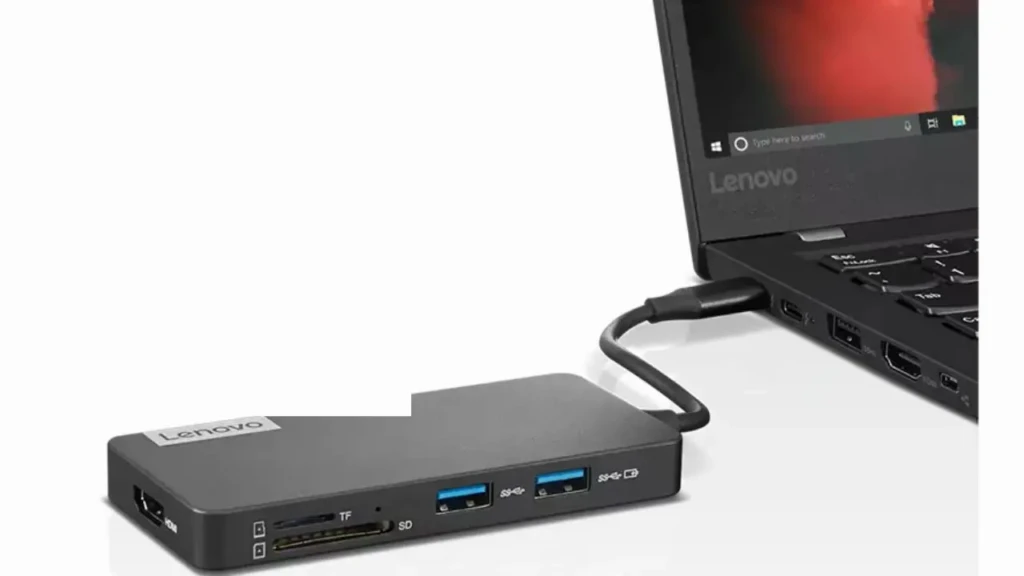 A black Lenovo USB-C hub connected to a Lenovo laptop via cable, showcasing ports including HDMI, SD/TF card slots, and dual USB-A (blue), with the laptop screen partially visible, highlighting peripheral expansion for data transfer or system recovery scenarios.