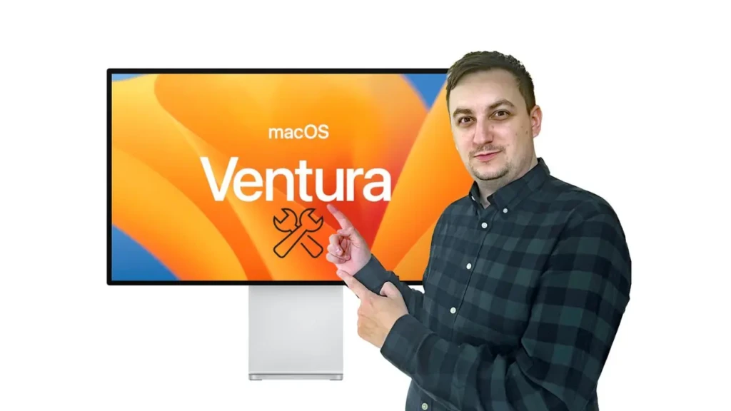 A person in a dark plaid shirt pointing toward a monitor displaying “macOS Ventura” with a wrench-and-screwdriver icon, suggesting a tutorial or troubleshooting guide for the operating system, presented against a clean white background for instructional clarity.