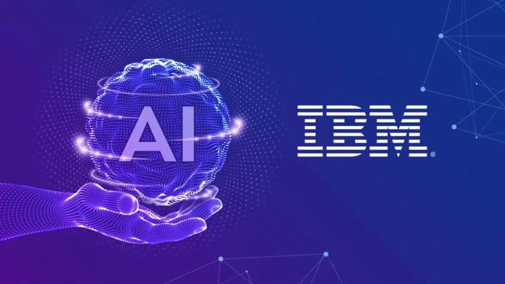 A futuristic illustration of a digital hand holding a glowing blue particle-based sphere labeled “AI,” with the IBM logo to the right on a deep blue gradient background, symbolizing IBM’s vision of human-centered, intelligent technology powered by AI.