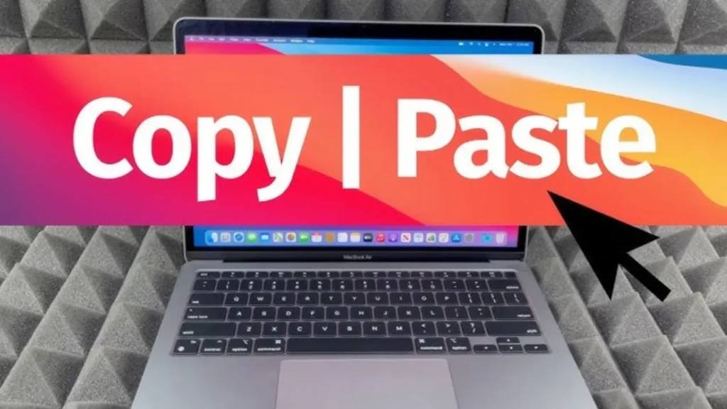 A MacBook Air on a gray acoustic foam background, partially overlaid by a vibrant red-to-orange banner with the text “Copy | Paste” in bold white font and a black cursor arrow pointing toward the screen, serving as a visual header for a macOS clipboard tutorial.
