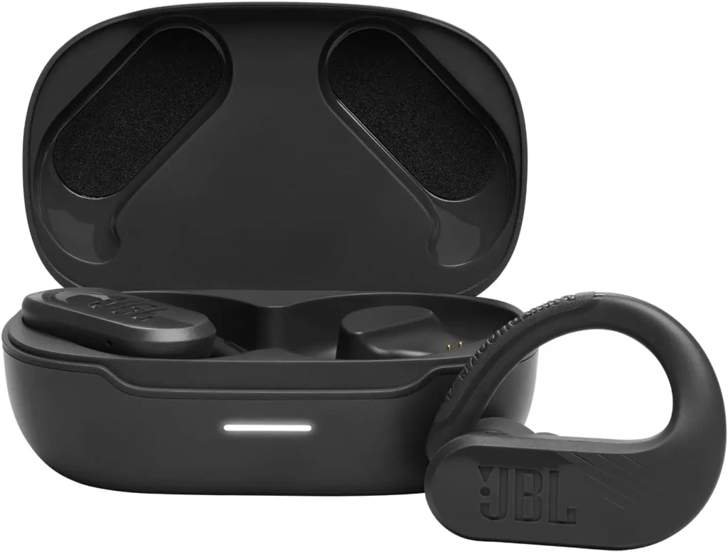 A black JBL wireless earbud with a secure hook design resting beside its open charging case, which holds one earbud and shows a glowing LED indicator, highlighting its sporty, sweat-resistant build and compact charging solution.
