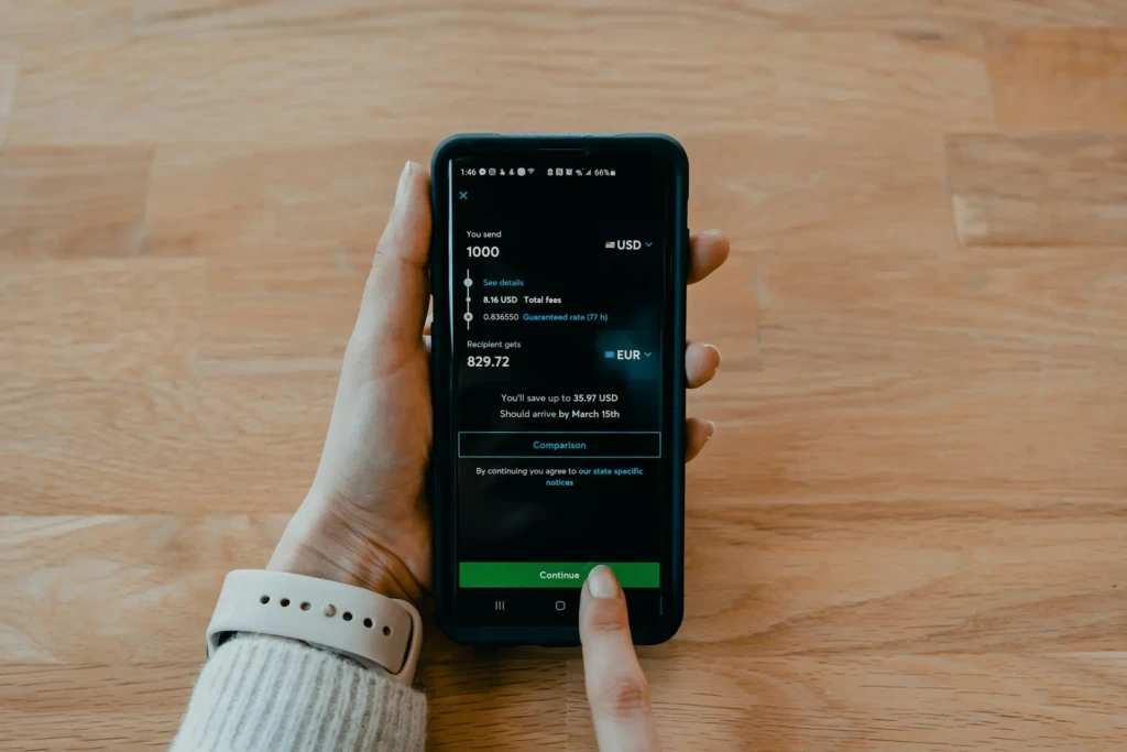A hand holding a smartphone displaying a currency conversion screen in Cash App: sending 1,000 USD (with $8.16 fees) to receive 829.72 EUR, noting a guaranteed exchange rate and estimated delivery by March 15th, highlighting its international money transfer and forex capabilities.