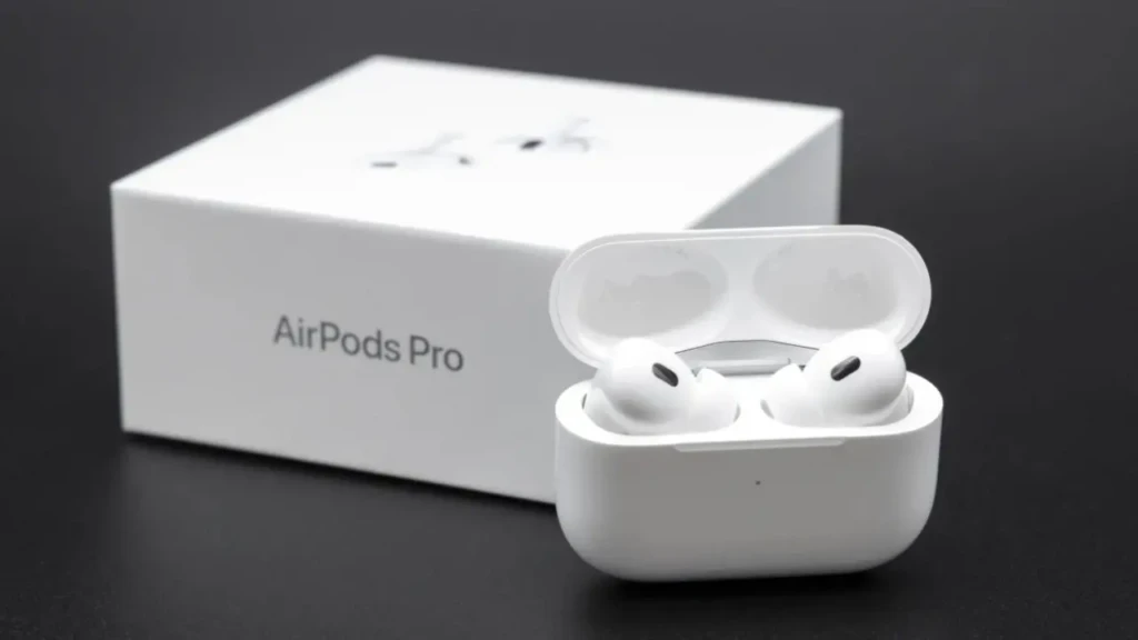 White AirPods Pro in an open charging case sit on a dark surface, with a box labeled "AirPods Pro" in the background, conveying a sleek, modern design.