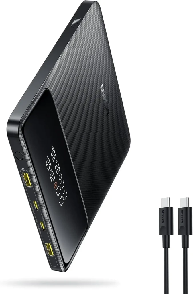 A black triangular-shaped Baseus power bank with a digital LED screen displaying time, battery level, and output status, multiple USB-C and USB-A ports on the side, and two black USB-C cables labeled “baseus,” emphasizing high-capacity, multi-device charging in a modern angular form factor.