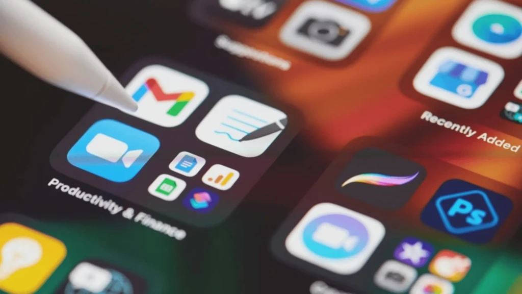 A close-up of an iPhone screen with a folder labeled “Productivity & Finance,” containing app icons including Gmail, Notes, Zoom, and others, with an Apple Pencil tip hovering over the folder, symbolizing curated digital workflows and intentional app organization for efficiency.
