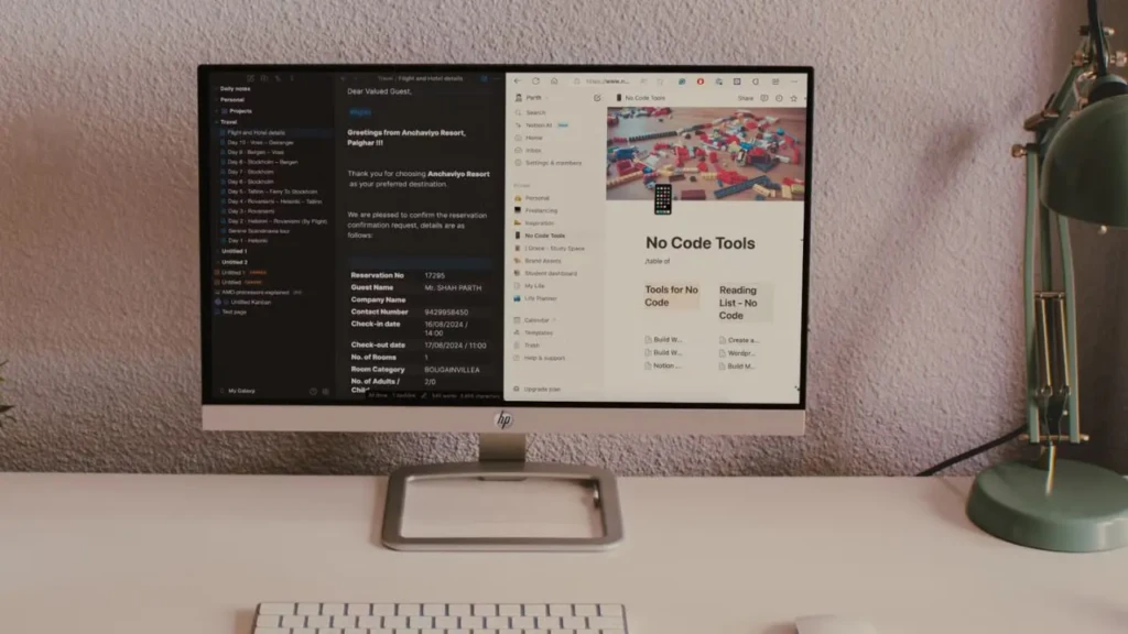 An HP monitor on a desk displaying a split-screen workflow: left shows a dark-mode note with travel itinerary and reservation details; right shows a Notion page titled “No Code Tools” with embedded tables, images, and sidebar navigation, illustrating productivity integration in a real-world workspace setting.
