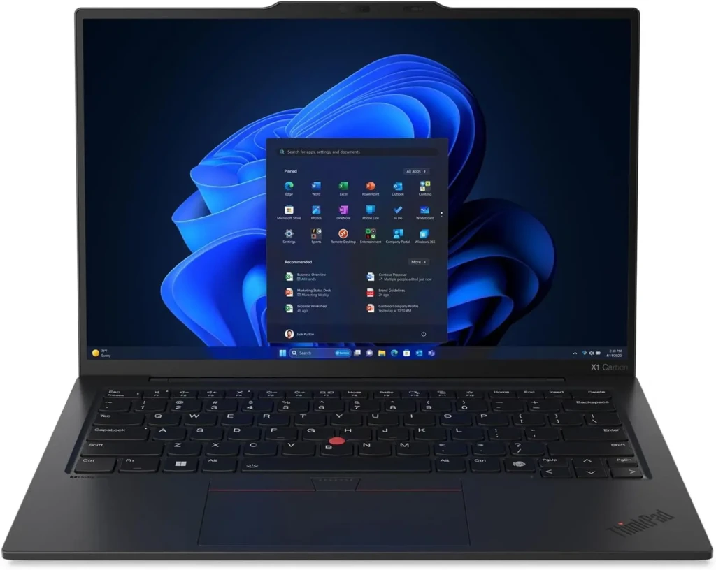 A black Lenovo ThinkPad X1 Carbon laptop open to the Windows 11 Start menu, with pinned apps (Edge, Word, Excel, etc.) and recommended items visible against the default blue wave wallpaper, illustrating a professional business-class device with enterprise-ready software integration.