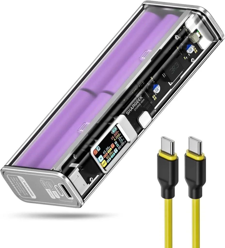 A transparent-shelled SHARGEK STORM2 Slim power bank revealing internal purple lithium batteries and circuitry, with a color OLED display showing real-time voltage, current, and temperature, alongside two yellow-tipped USB-C cables, illustrating advanced diagnostics and modular engineering.