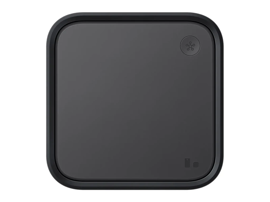 A matte black square smart hub with rounded corners, featuring a subtle network-icon button in the top-right and two small indicator lights at the bottom-right, presented against a clean white background to emphasize its minimalist, modern aesthetic.