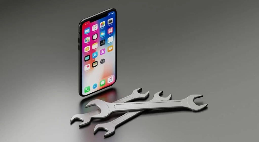 A black iPhone standing upright on a gray surface beside three crossed metallic wrenches, symbolizing device repair, diagnostics, or technical maintenance.