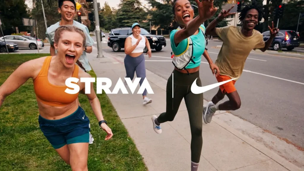 A dynamic street-running scene with four joyful runners, overlaid with the merged “STRAVA | NIKE” branding, suggesting collaboration or coexistence of the two platforms in modern fitness culture, rather than strict competition.