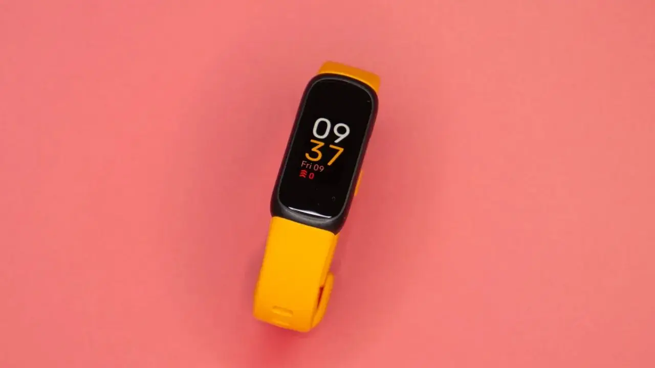 A yellow smartwatch with a black screen displays the time "09:37" in bold white and orange digits. It rests on a solid pink background, conveying a modern and vibrant tone.