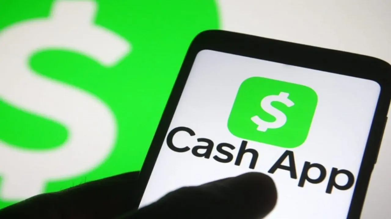 A smartphone displays the Cash App logo and name in bold text. In the background, a large green dollar sign is visible, conveying a financial theme.