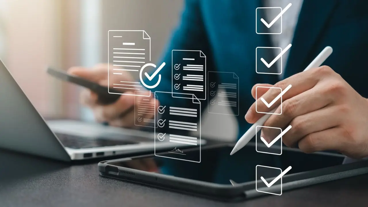 Close-up of hands using a tablet and stylus, with a laptop nearby. Digital icons of checklists and documents float above, symbolizing organization and productivity.