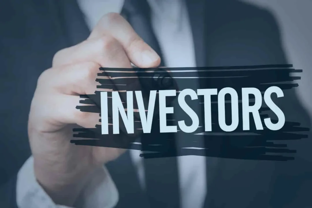 A person in a suit writes "INVESTORS" with a marker on a transparent screen. The word is bold and central, conveying a business theme.