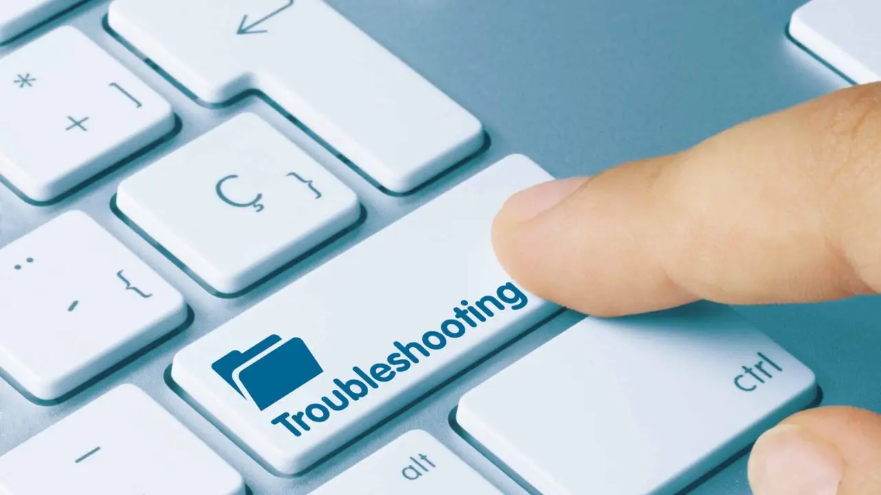 A finger presses a white key labeled "Troubleshooting" with a blue folder icon on a computer keyboard. The tone is focused and technical.