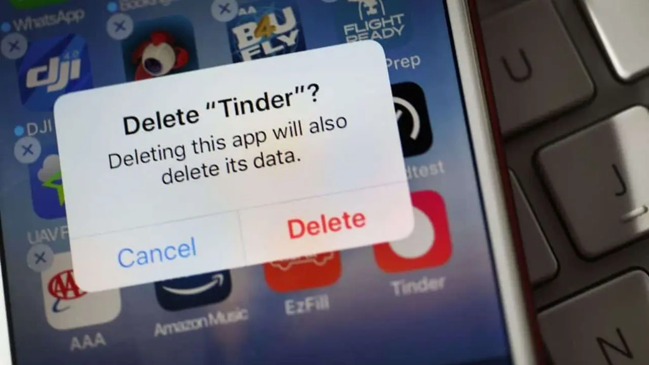 Close-up of a smartphone screen showing a pop-up message asking to delete the Tinder app, with "Cancel" and "Delete" options, reflecting decision-making.
