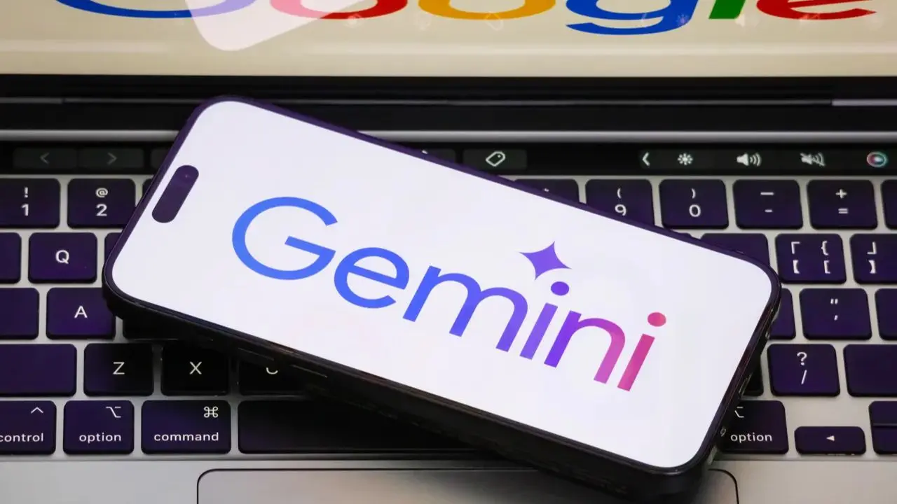 Smartphone displaying "Gemini" with a star icon, rests on a laptop keyboard. Vibrant colors and Google logo above convey tech innovation focus.