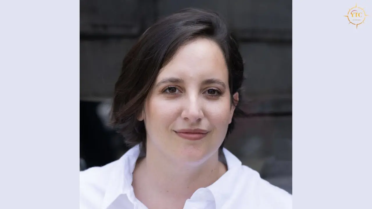 Close-up portrait of a woman with dark hair and brown eyes, wearing a white collared shirt.